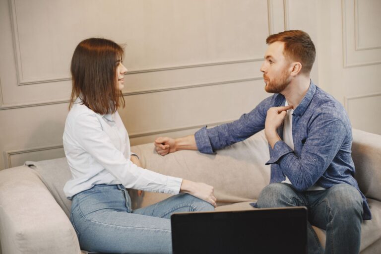 Pareja conversando de forma cercana y seria en un sofá