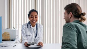 Profesional sanitaria conversando con un paciente al otro lado de la mesa durante una consulta